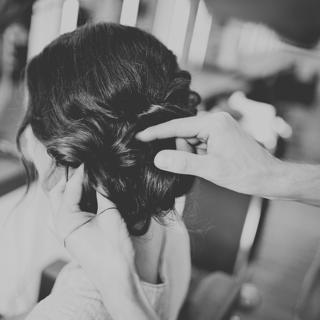 Person getting a stylish updo with intricate curls and pins in a salon.